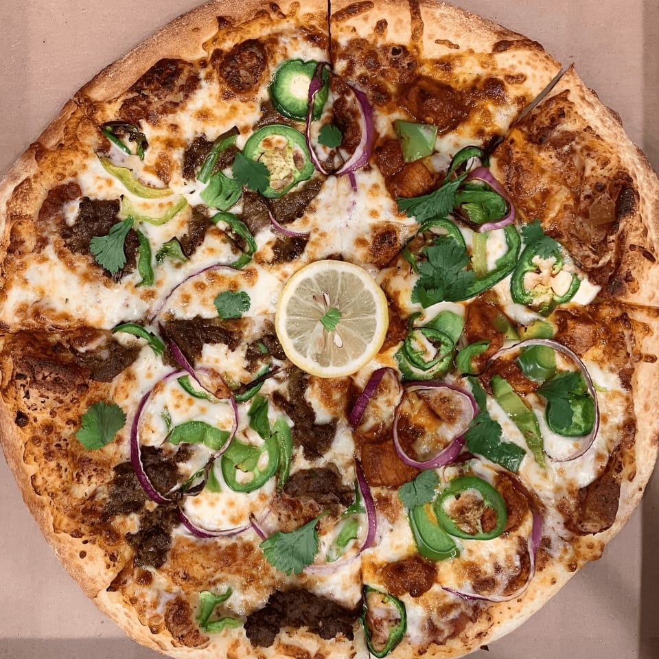Space City Pizza with beef, jalapeños, red onion, cilantro, and a lemon slice.
